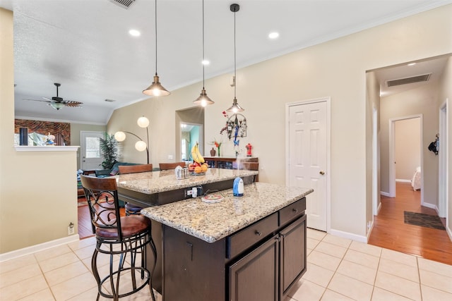 kitchen featuring light tile patterned floors, a kitchen bar, visible vents, and crown molding