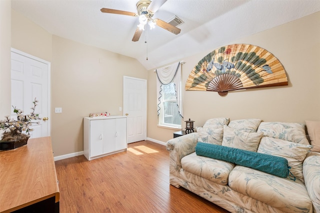 living room with light wood-type flooring, visible vents, lofted ceiling, and baseboards