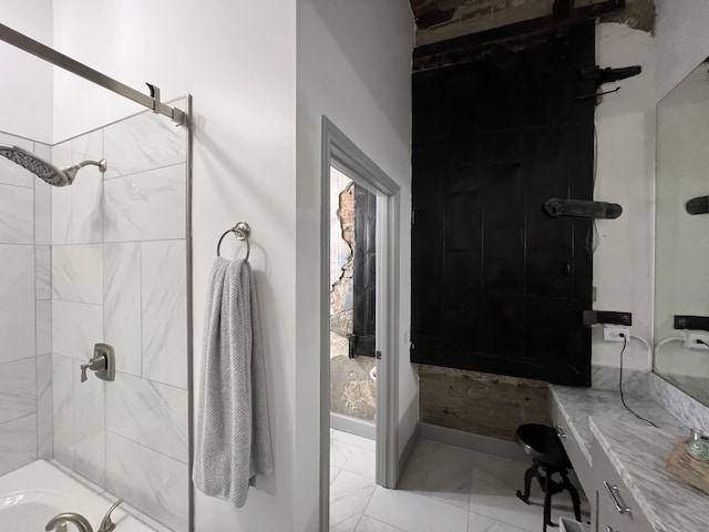 full bath featuring marble finish floor, a tile shower, and vanity