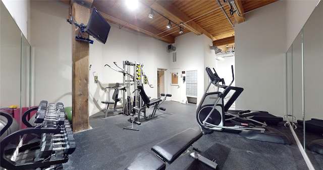 exercise room with wooden ceiling, a towering ceiling, and track lighting