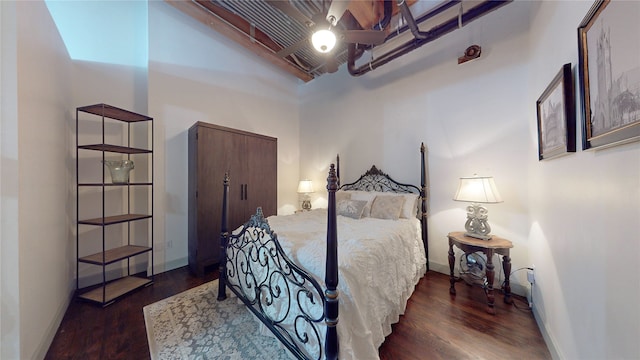 bedroom with a towering ceiling, baseboards, and dark wood-style flooring