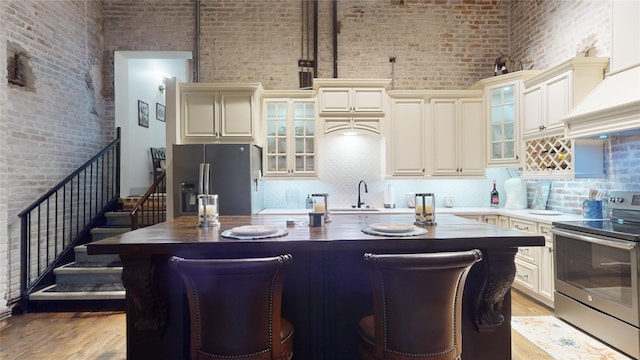 kitchen with a breakfast bar, appliances with stainless steel finishes, a kitchen island, a sink, and light wood-type flooring