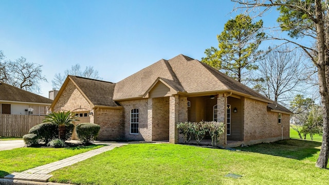 french country inspired facade featuring a garage, a front yard, brick siding, and fence