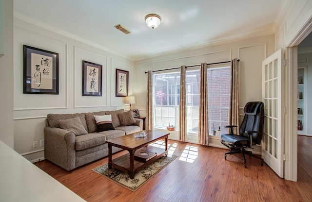 living room featuring ornamental molding, visible vents, and a decorative wall