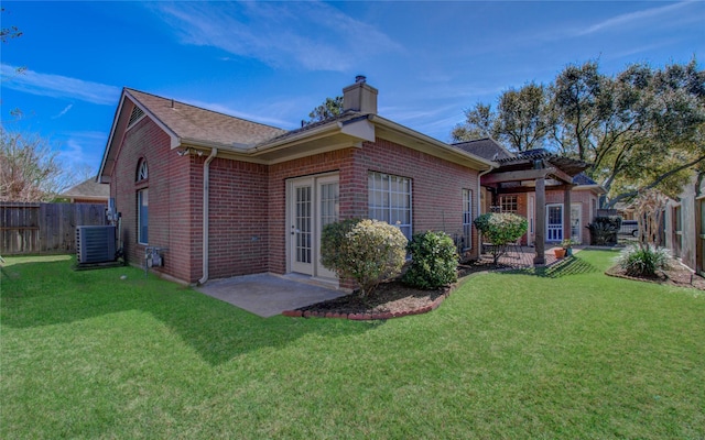 back of property with a chimney, fence, a lawn, and brick siding