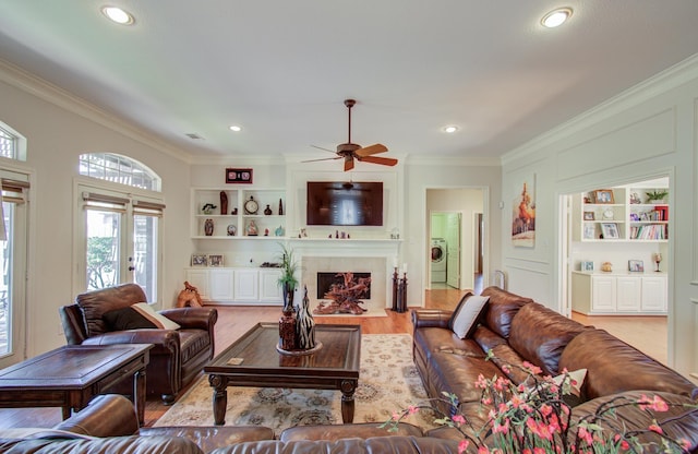 living area with built in features, washer / clothes dryer, and crown molding