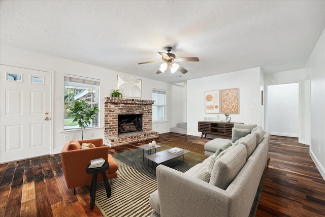 living room with a ceiling fan, a brick fireplace, a textured ceiling, wood finished floors, and baseboards