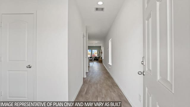 hallway featuring light wood-style flooring, visible vents, and baseboards