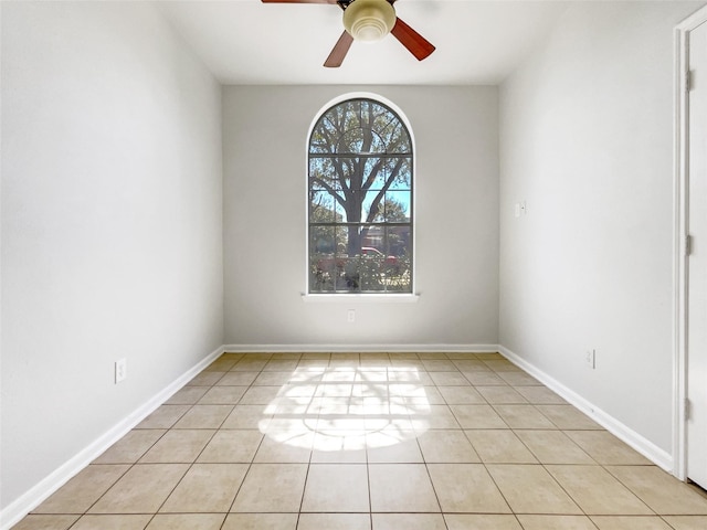 spare room with light tile patterned floors, a ceiling fan, and baseboards