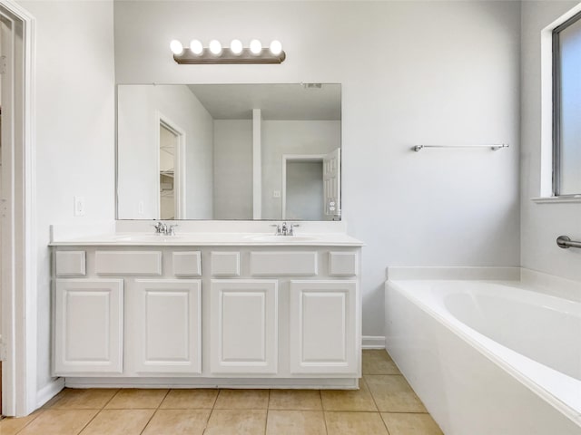 bathroom featuring tile patterned flooring, a garden tub, double vanity, and a sink