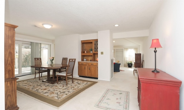 dining space featuring light carpet, visible vents, a textured ceiling, and recessed lighting