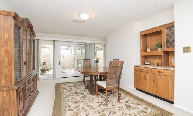 dining area with baseboards, visible vents, and light colored carpet