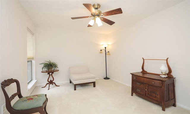 sitting room with baseboards, a ceiling fan, and light colored carpet