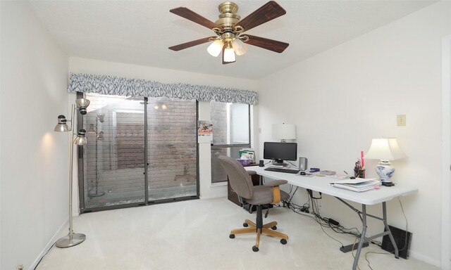 carpeted home office with ceiling fan and baseboards