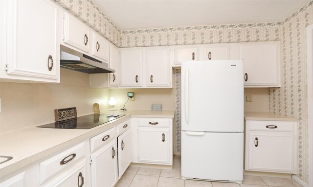 kitchen with freestanding refrigerator, light countertops, under cabinet range hood, and black electric cooktop