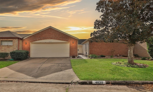 view of front of home featuring a garage, a front yard, concrete driveway, and brick siding