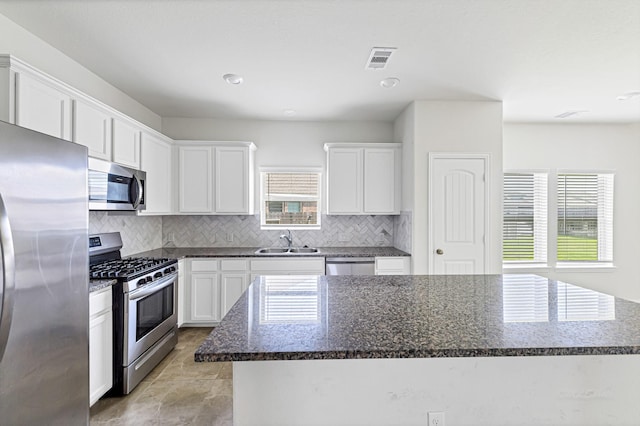 kitchen featuring visible vents, backsplash, appliances with stainless steel finishes, white cabinetry, and a sink