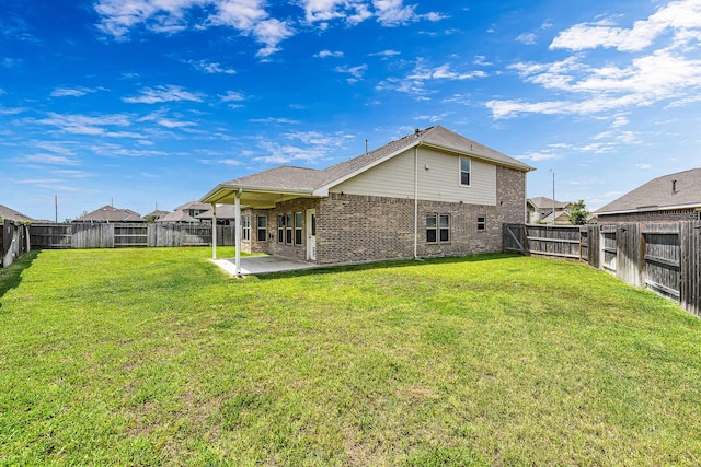 rear view of house featuring a patio area, a fenced backyard, a yard, and brick siding