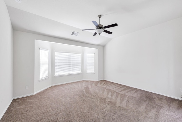 carpeted spare room featuring lofted ceiling, ceiling fan, visible vents, and baseboards