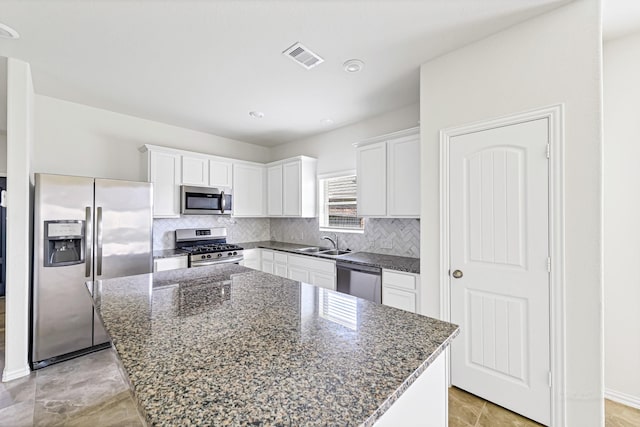 kitchen featuring a center island, backsplash, appliances with stainless steel finishes, white cabinets, and a sink