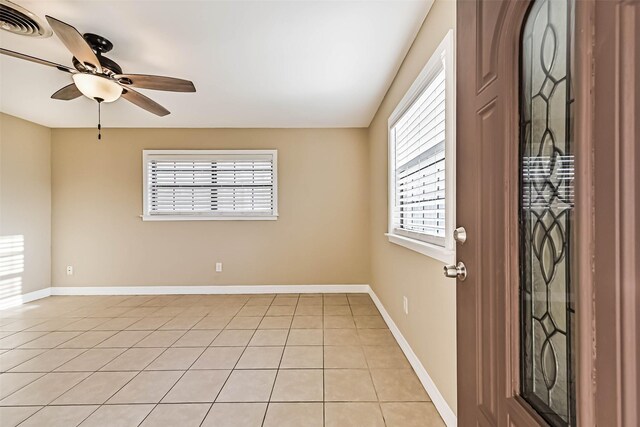 unfurnished room with light tile patterned floors, ceiling fan, visible vents, and baseboards