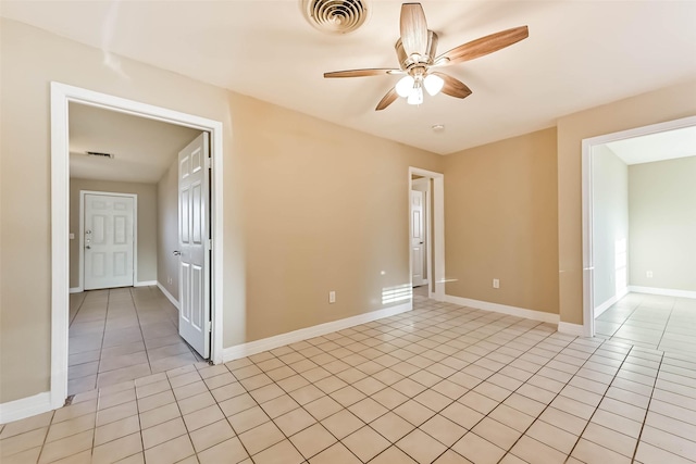 empty room featuring light tile patterned floors, ceiling fan, visible vents, and baseboards