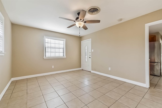 spare room featuring visible vents, light tile patterned flooring, a ceiling fan, and baseboards