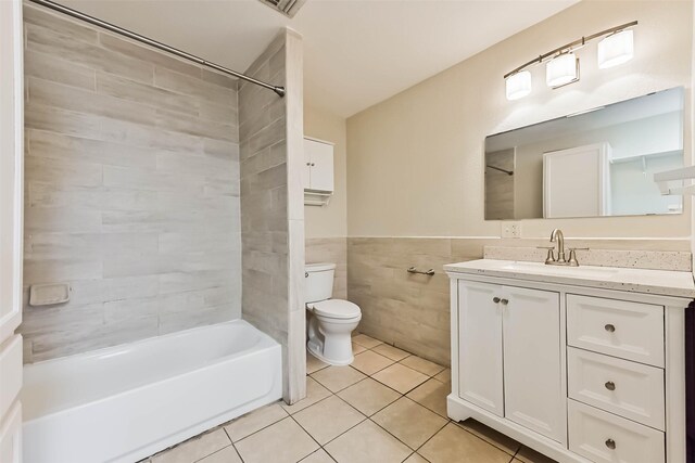 full bath with tile walls, bathtub / shower combination, toilet, wainscoting, and tile patterned floors