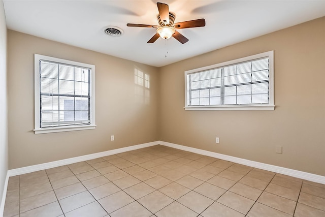 spare room with a ceiling fan, visible vents, and baseboards