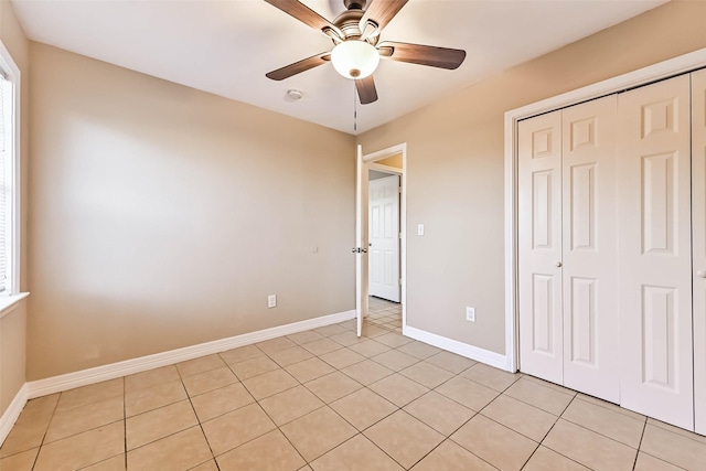 unfurnished bedroom featuring a ceiling fan, a closet, baseboards, and light tile patterned floors