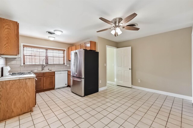 kitchen featuring a sink, light countertops, backsplash, freestanding refrigerator, and dishwasher