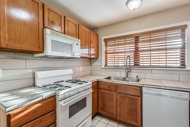 kitchen featuring tile counters, white appliances, a healthy amount of sunlight, and a sink