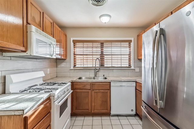 kitchen with tasteful backsplash, light countertops, visible vents, a sink, and white appliances