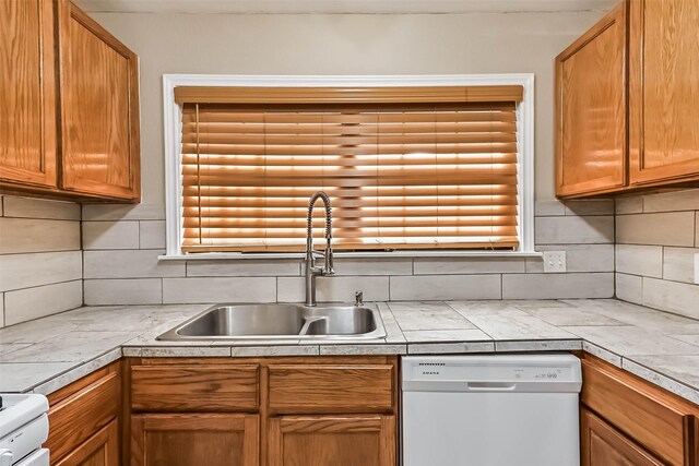 kitchen with plenty of natural light, tasteful backsplash, range, dishwasher, and a sink