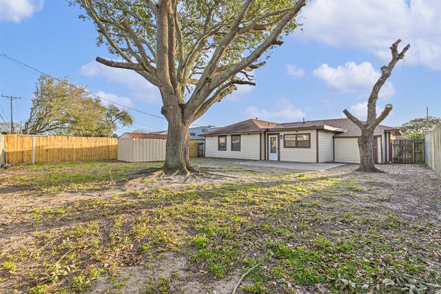 rear view of property featuring an outbuilding, a storage shed, a patio area, and a fenced backyard