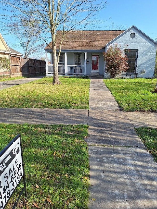 ranch-style home with a porch, a front yard, and fence