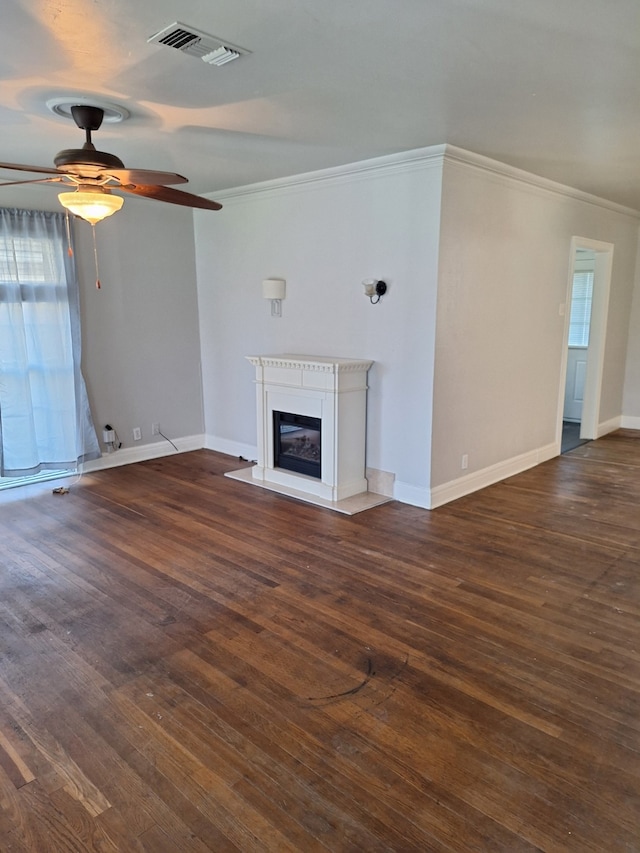 unfurnished living room featuring dark wood finished floors, a glass covered fireplace, crown molding, and visible vents