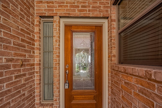 view of exterior entry featuring brick siding