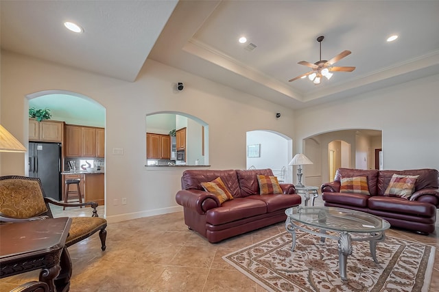 living area with a ceiling fan, visible vents, recessed lighting, arched walkways, and a raised ceiling