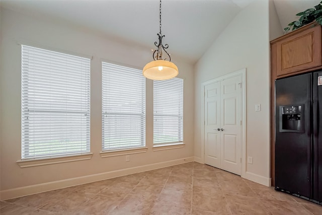 unfurnished dining area featuring baseboards, lofted ceiling, and light tile patterned flooring