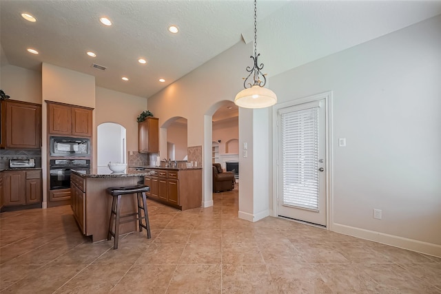 kitchen featuring arched walkways, visible vents, a center island, and black appliances