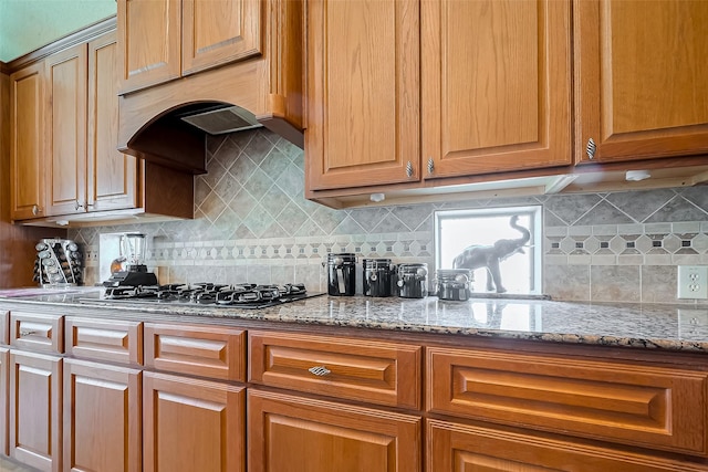 kitchen with gas cooktop, backsplash, and light stone countertops