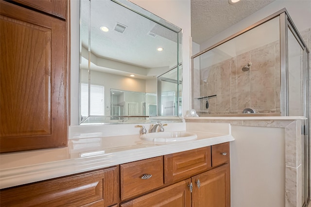 bathroom featuring visible vents, a textured ceiling, recessed lighting, a shower stall, and vanity