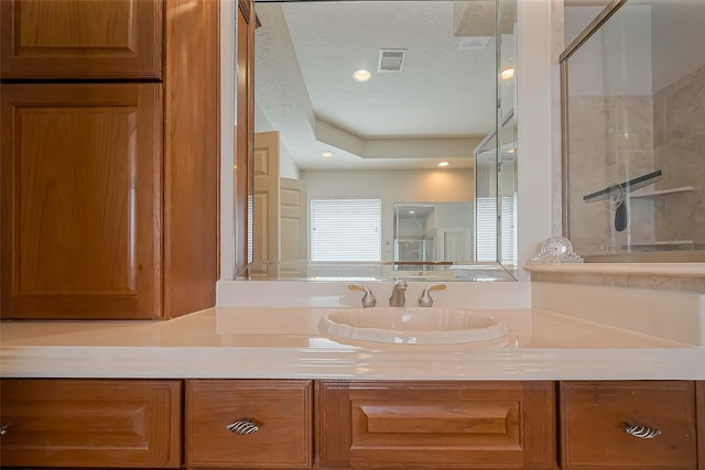 full bathroom with visible vents, a shower stall, a textured ceiling, and vanity