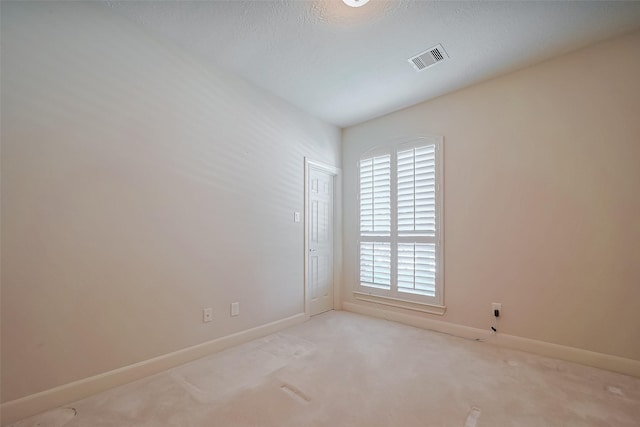 carpeted spare room featuring visible vents and baseboards