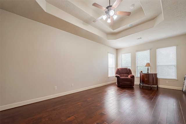 unfurnished room featuring visible vents, a raised ceiling, dark wood-type flooring, and baseboards