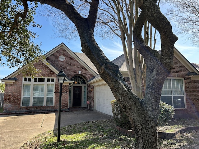 view of front facade with a garage, driveway, roof with shingles, and brick siding