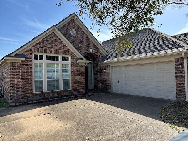 ranch-style home with brick siding, driveway, an attached garage, and roof with shingles