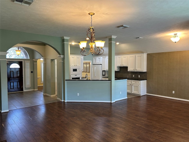 kitchen with white appliances, dark countertops, dark wood finished floors, and visible vents