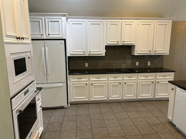 kitchen with backsplash, white cabinetry, dark stone counters, white appliances, and tile patterned floors